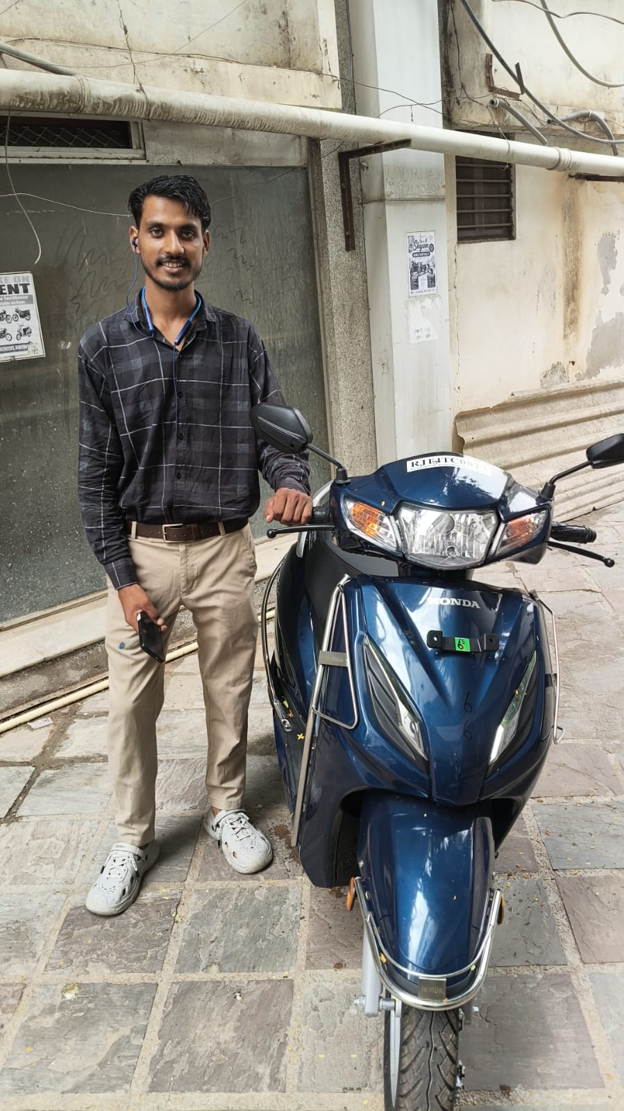 Customer standing with a blue Honda Activa scooter rental